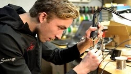 A student solders wire components by hand for the Wisconsin Electric Car Racing teams' competition vehicle