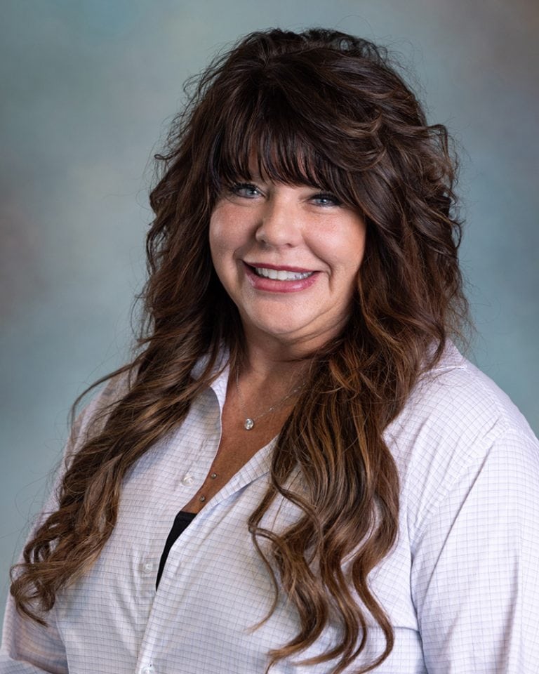Professional portrait of Diana Cizmas with long wavy hair, smiling, wearing a white shirt, against a soft background, for optimal image SEO.