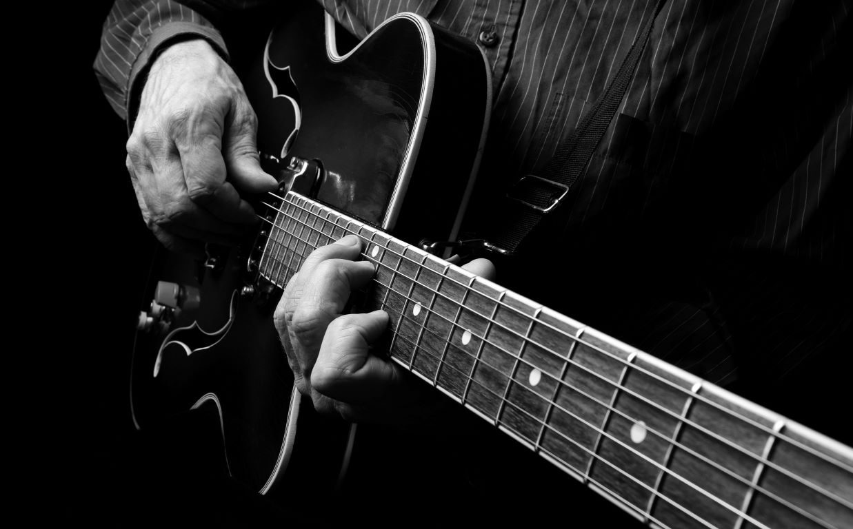 black and white photo of a man playing a guitar